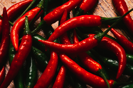 red and green chili peppers  close up on wooden backgroundの写真素材