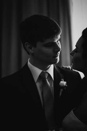 Black white photography beautiful young  couple standing near the windowの写真素材