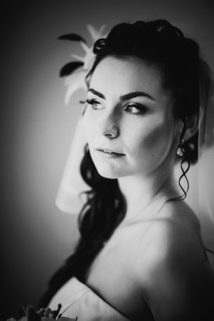 Black white photography beautiful young happy bride standing near the windowの写真素材
