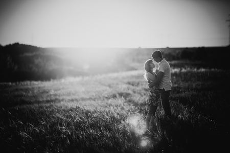 Black white photography romantic couple standing  and kissing on background summer meadow sunflower  sunsetの写真素材
