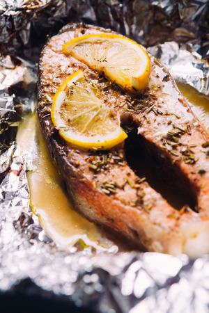 fish steak baked with lemon and herbs  in foilの写真素材