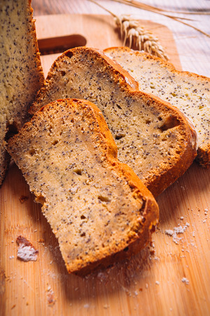 Close slice of  fresh bread with poppy seeds on a wooden backgroundの写真素材