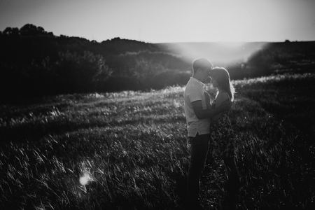 Black white photography romantic couple standing  and kissing on background summer meadow sunsetの写真素材