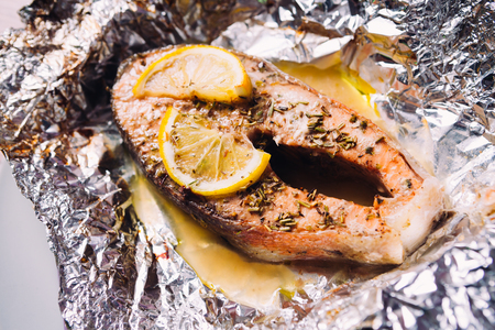 fish steak baked with lemon and herbs  in foilの写真素材