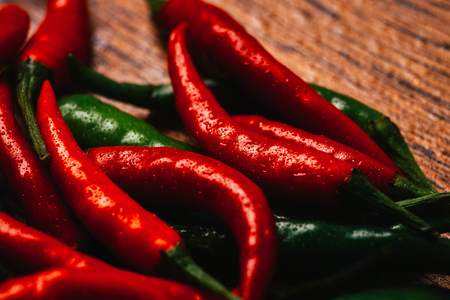 red and green chili peppers  close up on wooden backgroundの写真素材