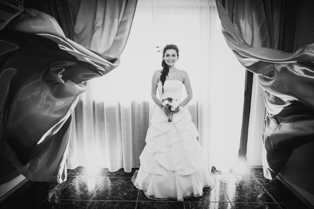 Black white photography beautiful young happy   bride standing near the windowの写真素材