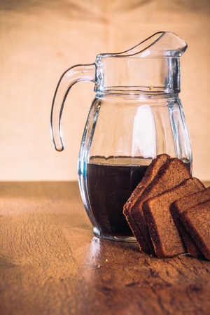 Russian brew in jug  and loaf of rye flour on wooden backgroundの写真素材