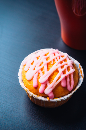 cupcake with pink frosting  and red cup on a wooden backgroundの写真素材