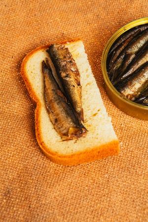 open can and sandwich with   of sprats on sackcloth backgroundの写真素材