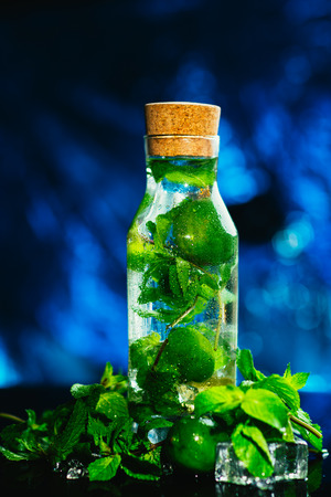 mojito bottle with lime and mint ice cube close-up on blue background.の写真素材