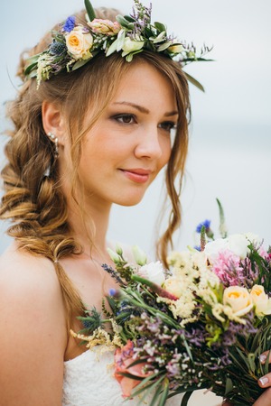 young bride with a bouquet of flowers standing on the background of the river.の写真素材