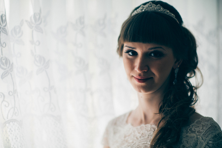 portrait of a young bride smiling and standing near a window.の写真素材