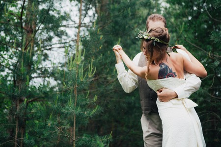 Bride and groom fooling around on the background of leaves and forest.の写真素材