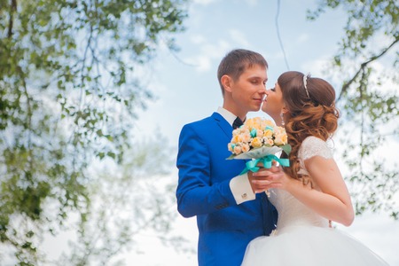 bride and groom kissing on the background of trees.の写真素材