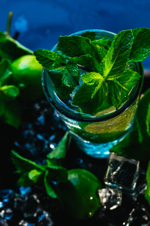 glass of mojito with lime and mint ice cube close-up with red straw on blue background.の写真素材