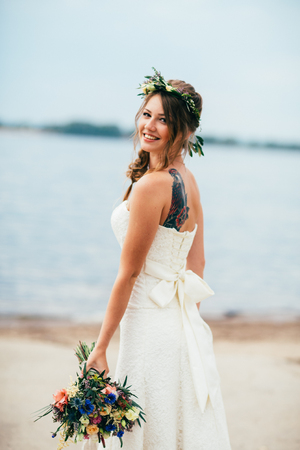 young bride with a bouquet of flowers standing on the background of the river.の写真素材