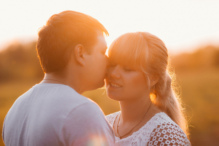 portrait of love story man and woman on the background of haystacks and sun.の写真素材