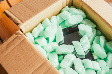 parcel of online shop, phone in a cardboard box on a green polystyrene.の写真素材