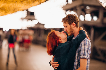 Happy couple embracing and kissing in the evening on a light garlands.の写真素材