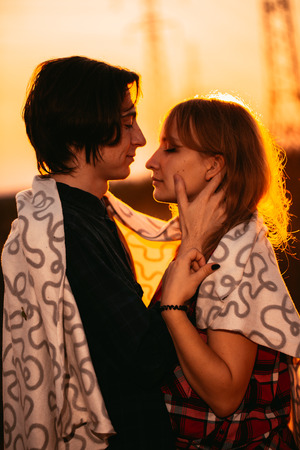 guy and the girl are standing against the sunset in a plaid.の写真素材