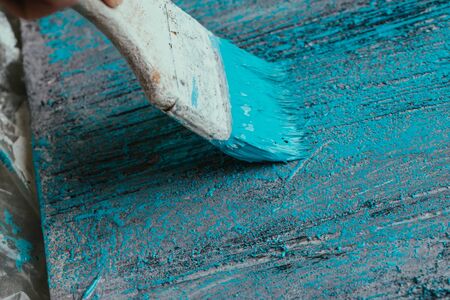 closeup hand use brush paint white blue on wood surface.の写真素材