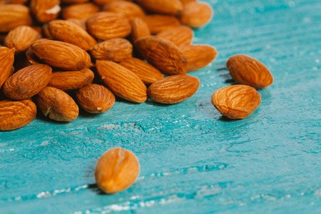 handful of almonds on a blue wooden background.の写真素材