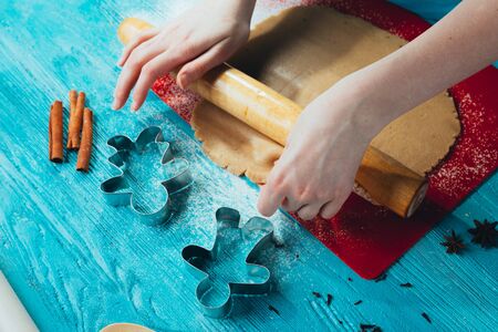 girl rolls the dough on the red board to blue wooden table.の写真素材