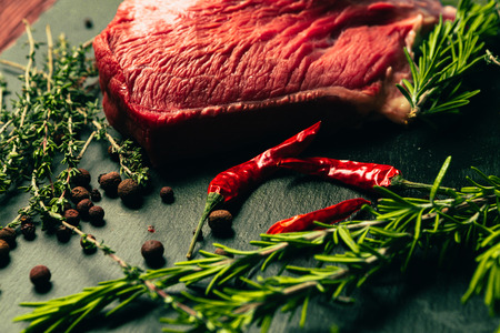 Raw beef meat with spices on slate stone kitchen boardの写真素材