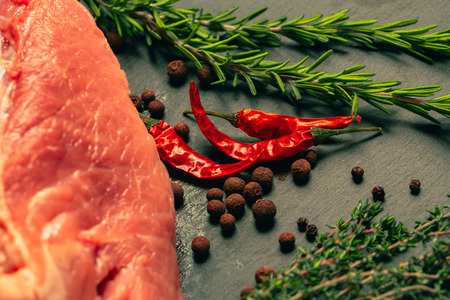 raw pork meat with spices on slate stone kitchen boardの写真素材