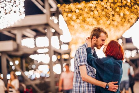 Happy couple embracing in the evening on a light garlandsの写真素材