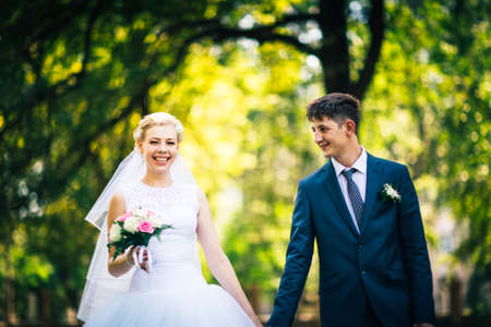portrait the bride and groom on the background of the park alleyの写真素材