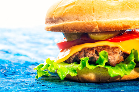 Cheeseburger closeup on a blue backgroundの写真素材