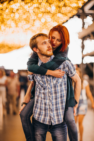 Happy couple embracing in the evening on a light garlandsの写真素材