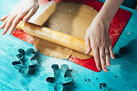 girl rolls the dough on the red board to blue wooden tableの写真素材