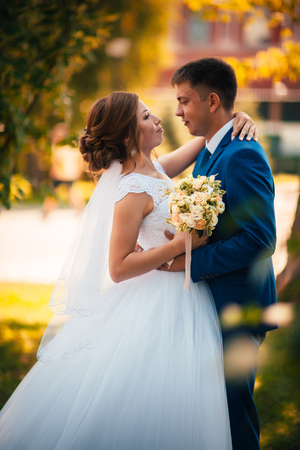 couple groom and bride against the background of orange leavesの写真素材