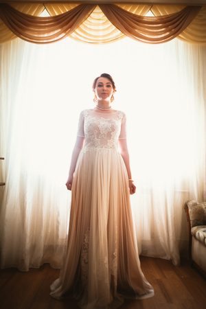 beautiful young bride near the window in full growthの写真素材