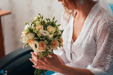 portrait of a young bride with a bouquet on a light backgroundの写真素材