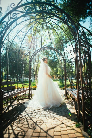 Young beautiful bride standing in a park gazebo.の写真素材