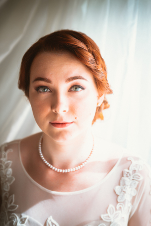 Portrait of a beautiful young bride near the windowの写真素材