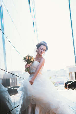 Bride and bouquet on backround mirror buildings.