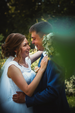 A groom and a bride hugging and kissing on nature park backgroundの写真素材