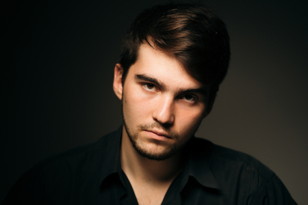 Young brunette guy on a dark backgroundの写真素材