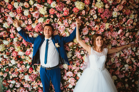 beautiful bride and groom on the background of a wall of flowersの写真素材