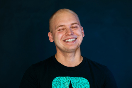 young guy balding in a vest on a dark backgroundの写真素材