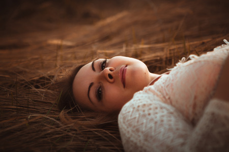 portrait of a girl lying on a field on a sunset background.の写真素材