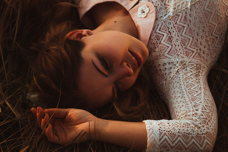 portrait of a girl lying on a field on a sunset background.の写真素材