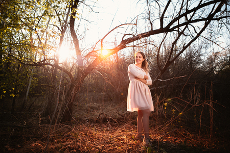 Beautiful girl standing in a field on a sunset background.の写真素材