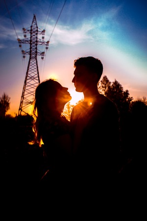 Silhouettes of a guy and girl in a field on a sunset background.の写真素材