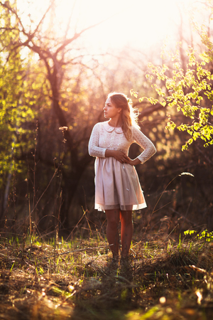 Beautiful girl standing in a field on a sunset background.の写真素材