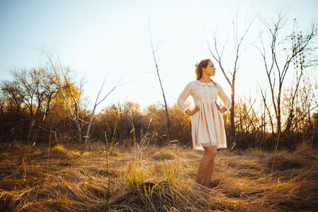 Beautiful girl standing in a field on a sunset background.の写真素材